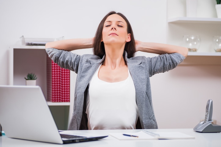 Young businesswoman is relaxing in her office. She is stretching her body.