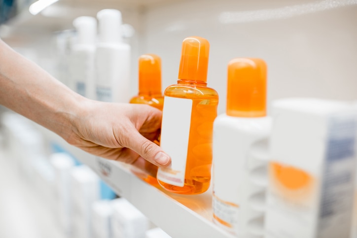 Taking sunscreen lotion from the shelves of the pharmacy store, close-up view