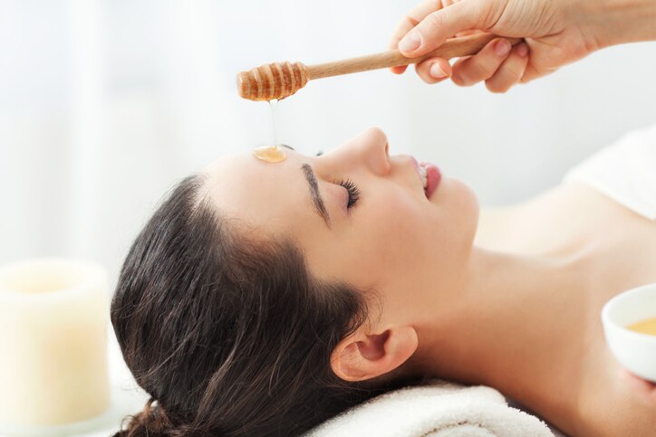 Woman having honey facial massage at spa salon