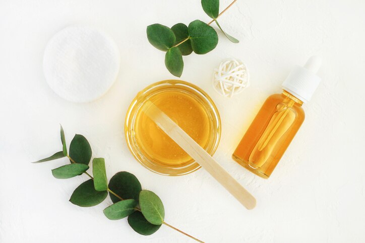 Yellow jars and bottle of facial mask top view with leaves white background