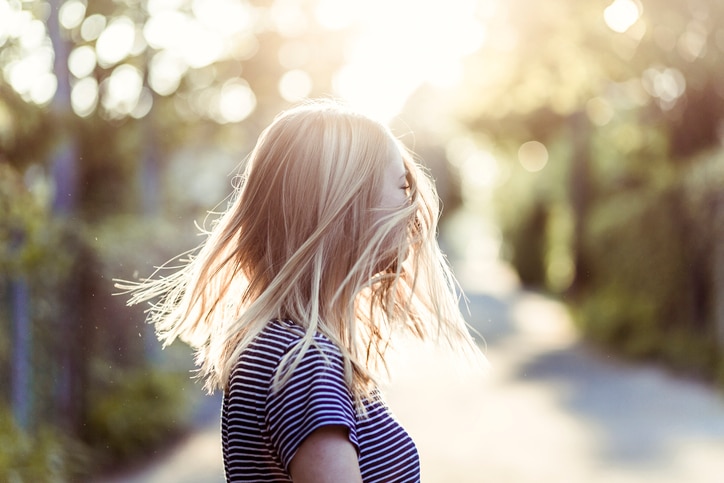 one young woman only, blond hair, shaking head, back lit