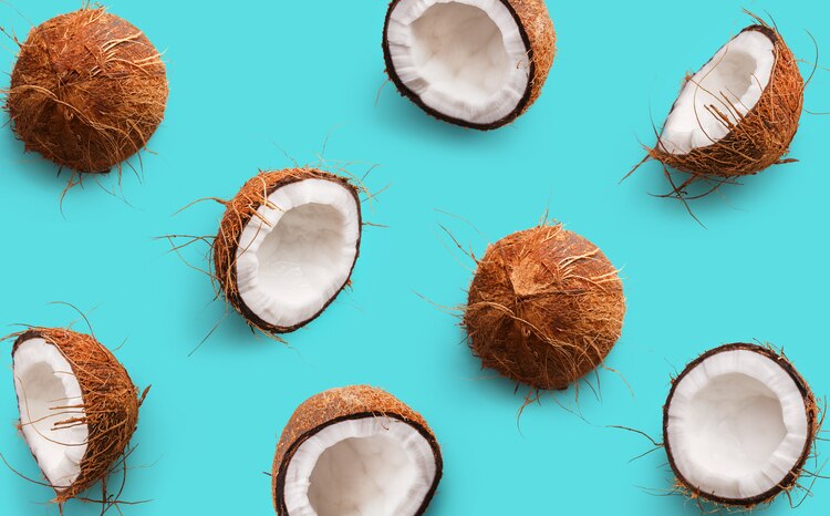 Coconut pattern on a blue background. Half and whole coconuts. Repetition concept. Top view