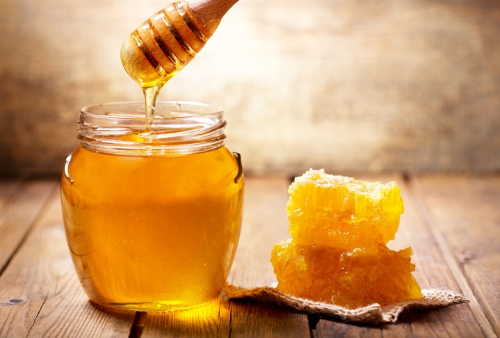 jar of honey with honeycomb on wooden table