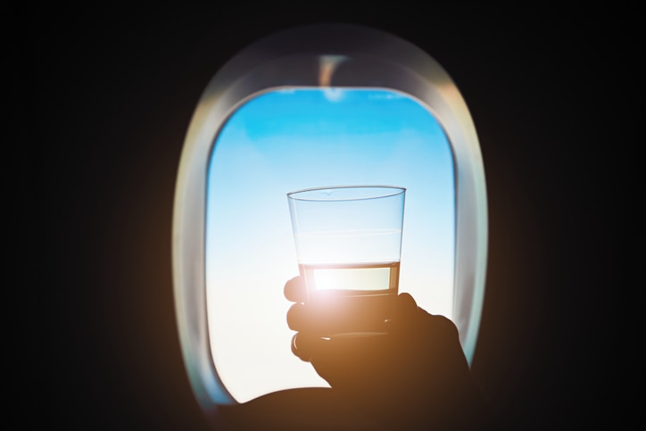 Comfortable traveling by airplane. Passenger is holding glass of the wine during the flight.