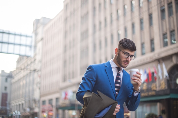 One man, handsome gentleman, relaxing outdoors in the city, holding coffee cup.