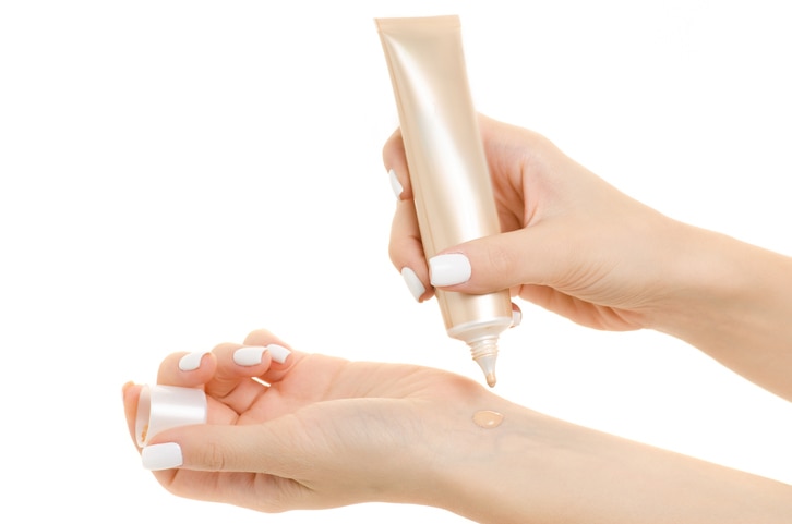 Female hand base cream beige on white background isolation