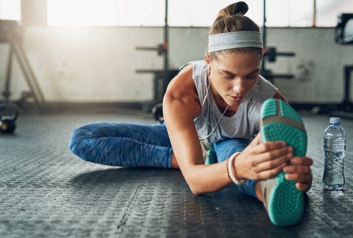 Shot of a young attractive woman stretching in a gym