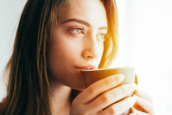 Young woman drinking coffee at home early in the morning