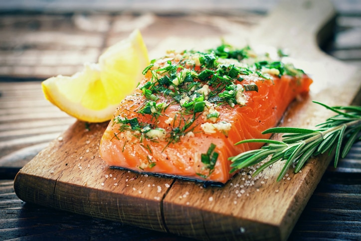 Raw salmon on a cutting board with fresh spices