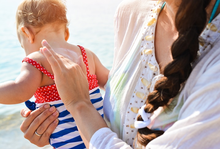 Mother applying sunblock cream on daughter shoulder