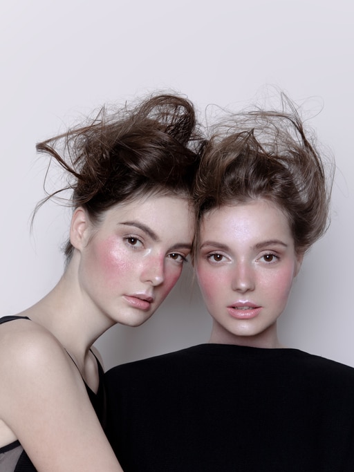 Two beautiful young women look alike sisters with creative artistic make-up and hairstyle Close-up Faces Fashion models Portrait Studio shot