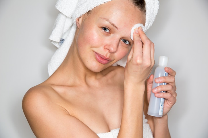 Beautiful brunette woman removing makeup from her face