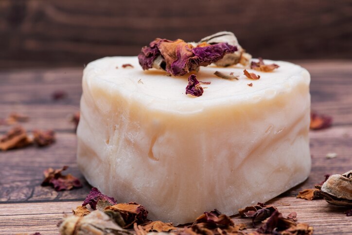 Heart shaped Goat milk Soap and dried roses on wooden background.