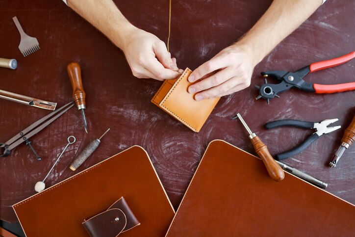 Human hands using handtool while producing leather item