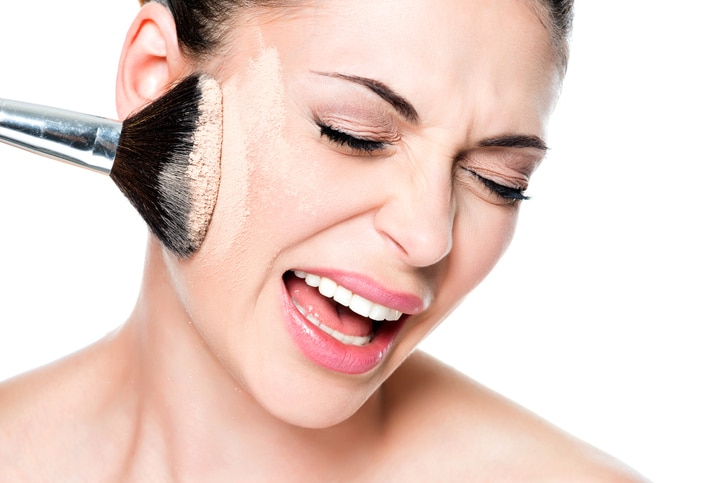 Face of a woman with  powder on the skin of cheek- isolated on white