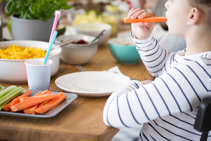 Close-up of kid eating carrot during breakfast. Healthy diet for child concept