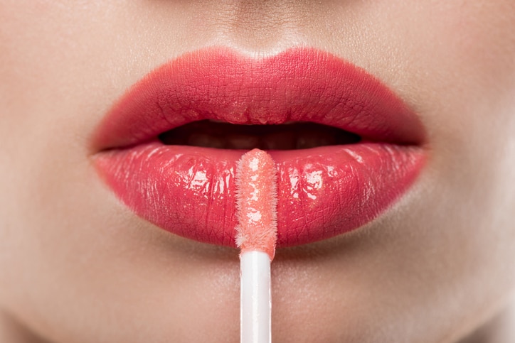 close up of young woman applying lip gloss