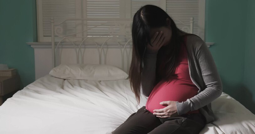 pregnant women sit on the bed and feel depression at home