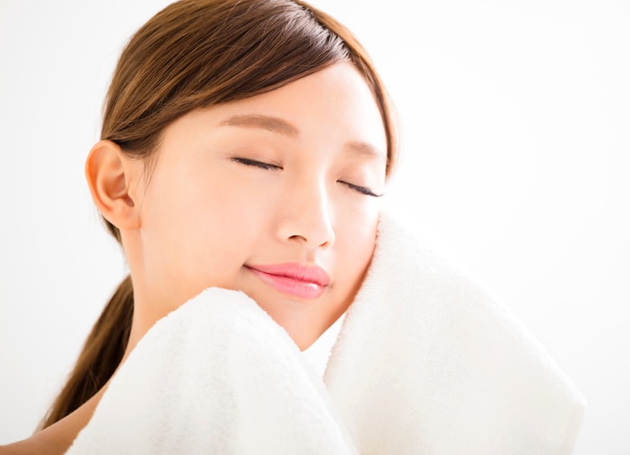 young woman cleaning her face with  towel