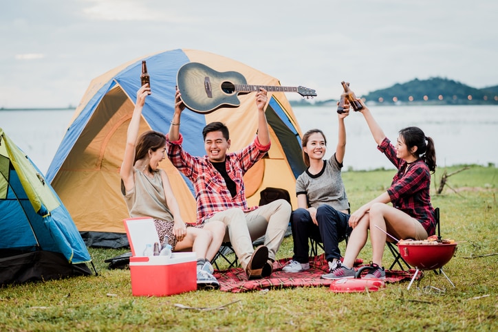 Happy Asian friends having a good time together while travel camping vacation trip by the lake