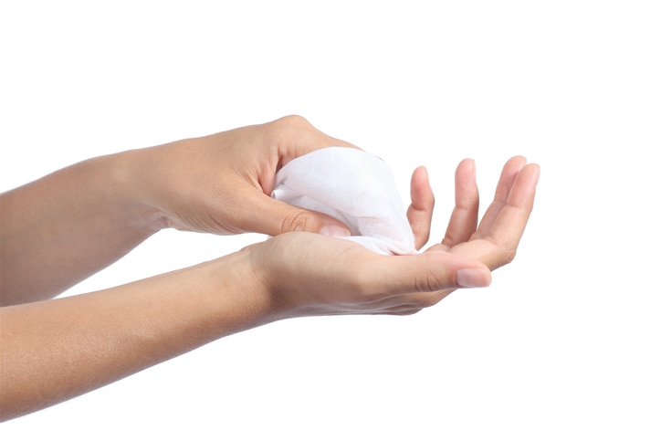 Woman cleaning her hands with a wet baby wipe isolated on a white background