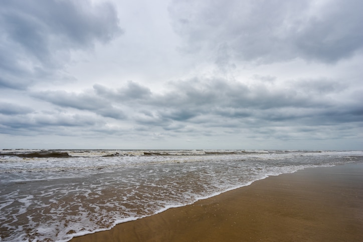 Sand beach, blue sea and white bubble wave in cloudy day