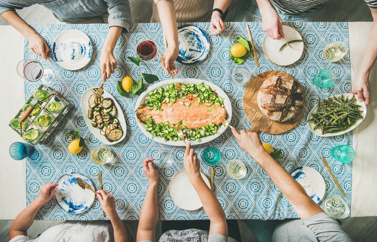 Family or friends summer party or seafood dinner. Flat-lay of group of mutinational people with different skin color at big table eating delicious food together. Summer gathering or celebration