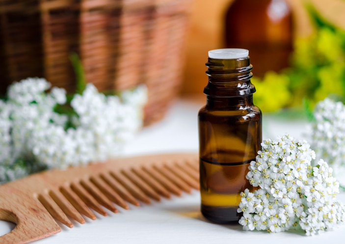 Small bottle of essential yarrow oil and hair comb