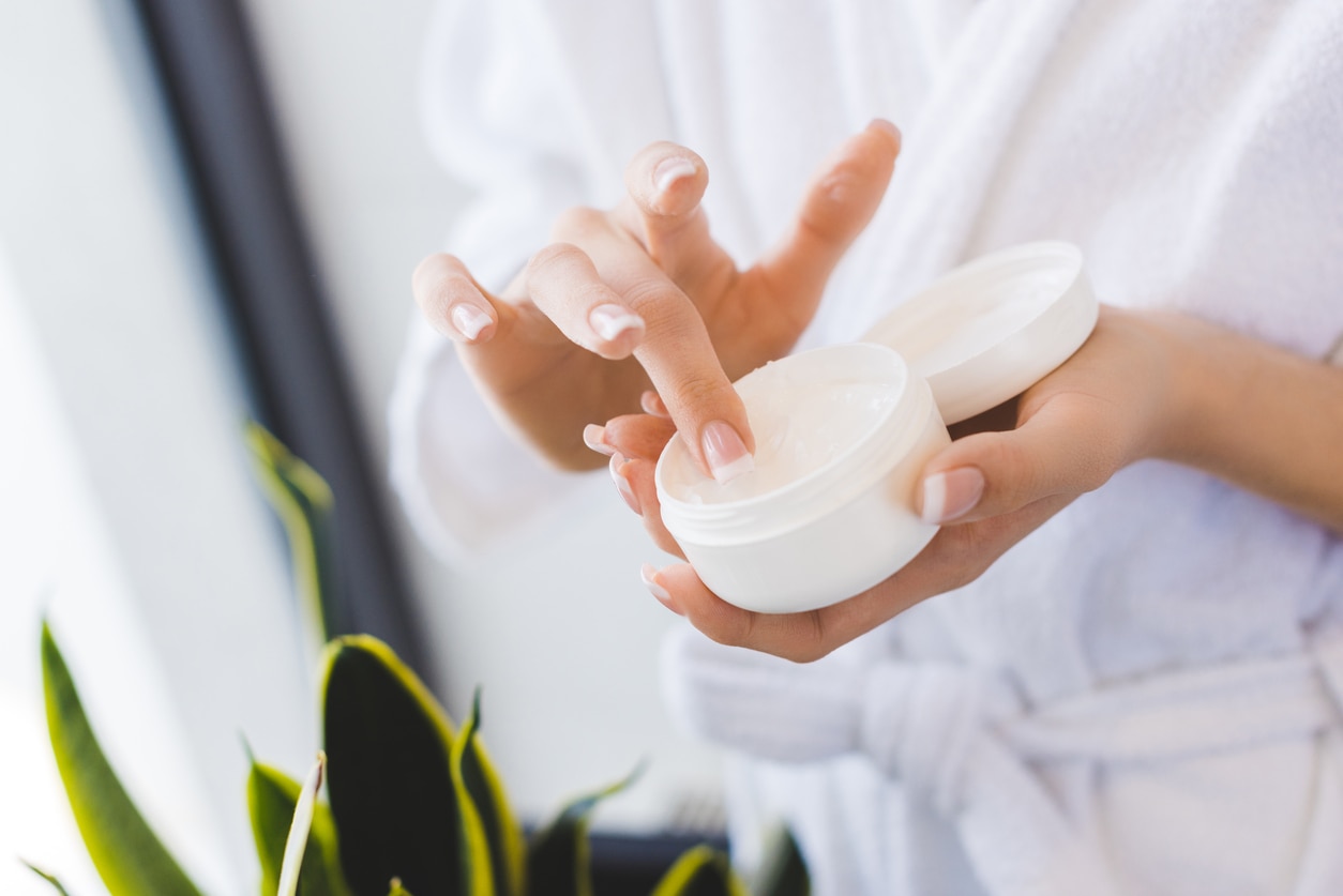 partial view of woman holding face cream in hands