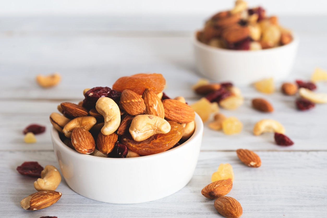 mixed nuts and dried fruit in wooden bowl on wooden table top view. Walnut, pistachio, almond, hazelnut, cashews, apricot, berry, banana, pineapple, Healthy food and snack