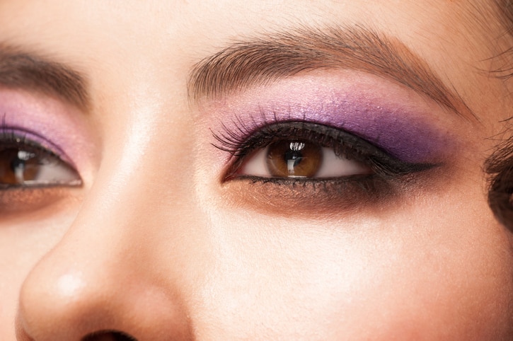 Close-up image of young asian woman eye with bright violet makeup