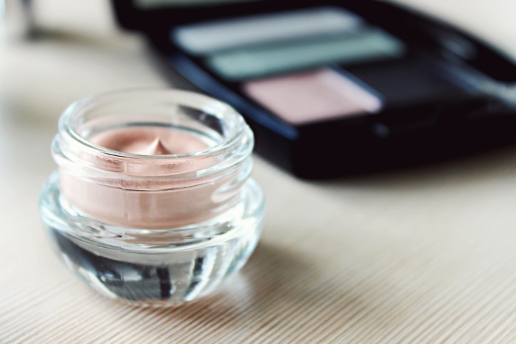 Set of eyeshadow and a cream primer on a dressing table