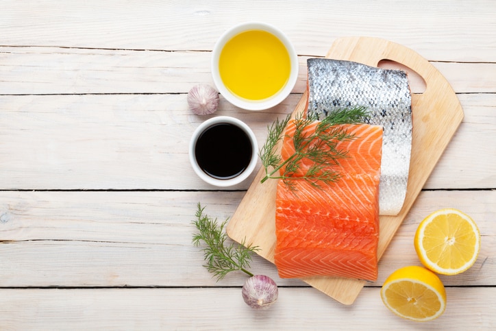 Salmon, spices and condiments on wooden table. Top view with copy space