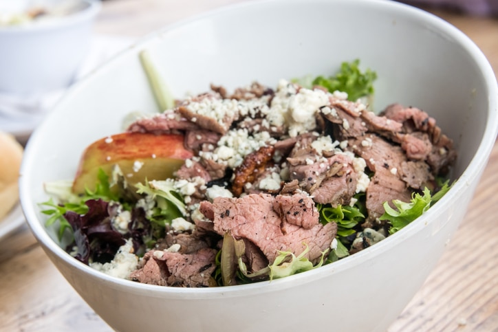 steak salad with blue cheese crumbles in a bowl close up