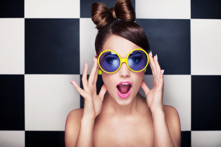 Attractive surprised young woman wearing sunglasses on checkered background, beauty and fashion concept