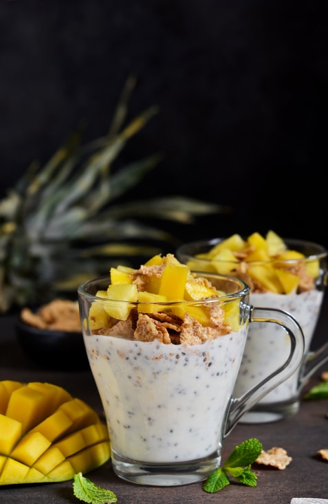 Summer light dessert - yoghurt with chia, muesli and a variety of fruits on a dark concrete background. Natural food.