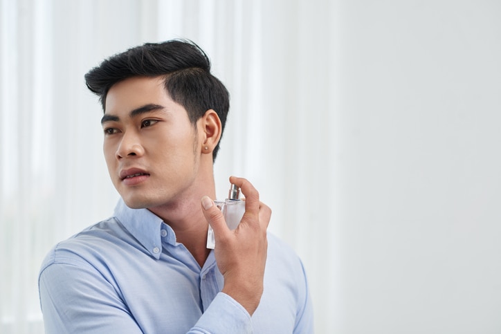 Vietnamese young man spraying perfume