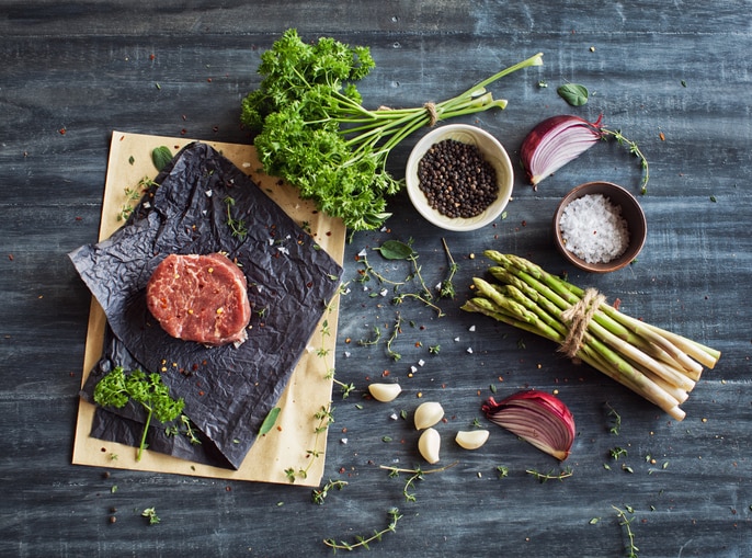 Raw tenderloin steak with seasoning, garlic, and asparagus