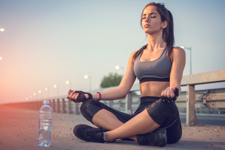 Young slim woman doing yoga exercises outdoors on the bridge.