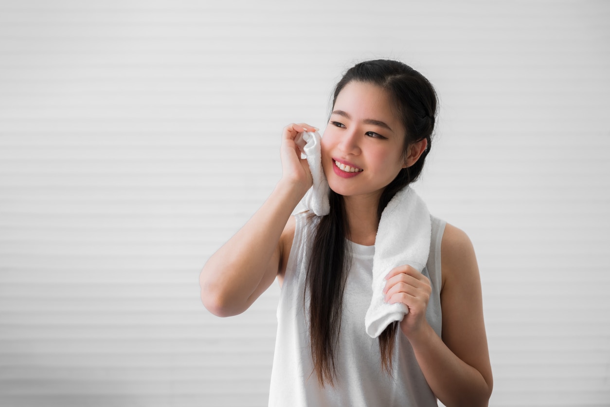 exercise helps To Deliver Oxygen And Nutrients, Portrait of happy beautiful asian woman using white towel wiping sweat from her face after exercise in home. Close up of healthy female or sports girl smile and wiping sweat with towel after workout.